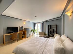 a bedroom with a white bed and a television at CozyNook Boutique Apartments - 3 thang 2 Street in Da Lat