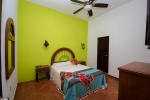 una camera da letto con pareti verdi e un letto con ventilatore di Departamentos Claussen a Mazatlán