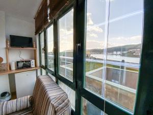 a room with a couch and a large window at Apartamentos Sapoconcho by ALÔGA in Cee