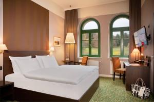 a bedroom with a bed and a desk and windows at Schlosshotel Blankenburg in Blankenburg