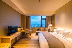ein Hotelzimmer mit einem großen Bett und einem TV in der Unterkunft Hotel Nikko Hai Phong in Haiphong