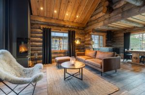 een woonkamer met een bank en stoelen en een open haard bij Wilderness Hotel Muotka & Igloos in Saariselkä
