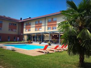 un hôtel avec une piscine, des chaises longues et un palmier dans l'établissement Le Domaine des Fontaines - Expérience, à Bernin
