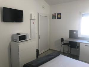 a small white room with a microwave and a desk at Beach House in Fos-sur-Mer