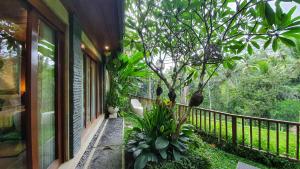 einen Balkon mit einem Baum an der Seite eines Hauses in der Unterkunft Puri Raya Villa in Ubud