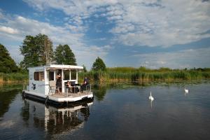 ein kleines Boot auf einem See mit Leuten darauf. in der Unterkunft Havel Cruiser - Hausboot-Flöße mit Stil in Brandenburg an der Havel