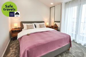 a bedroom with a bed with a pink and white blanket at Perla Residence Hotel & SPA in Podgorica