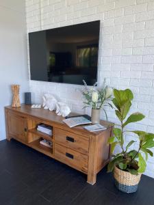 un centro de entretenimiento de madera con TV en una pared de ladrillo en Serenity by the Lake - Romantic Waterfront Couple's Getaway, en Marks Point