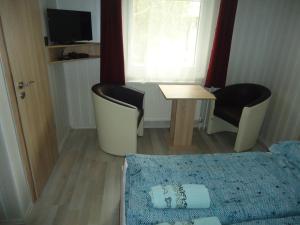 um pequeno quarto com uma cama, uma mesa e cadeiras em Deutsches Haus em Szabadkígyós