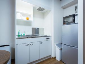 eine kleine Küche mit Spüle und Kühlschrank in der Unterkunft Ryujin Hotel Ukishima in Naha