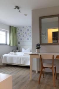 a bedroom with a bed and a table and a mirror at Der Landhof Wildrose in Stolpe
