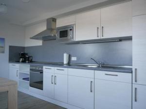 a kitchen with white cabinets and a sink and a microwave at Der Landhof Sonnenblume in Stolpe