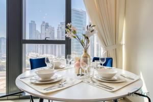 a white table with a vase of flowers on it at Stylish 1BR Apartment at Blvd Heights Downtown Dubai by Deluxe Holiday Homes in Dubai