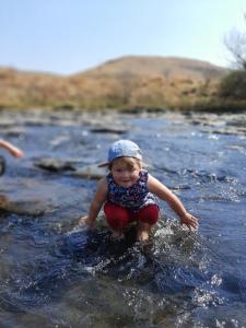 a little girl is playing in a river at Umzimkulu River Lodge in Underberg