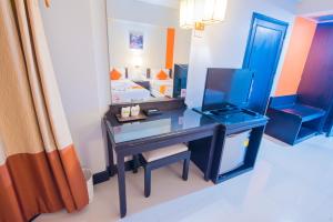 1 dormitorio con escritorio, cama y espejo en Asawann Hotel, en Nong Khai