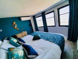 a bedroom with a bed with blue walls and windows at Le Paquebot in Villerville