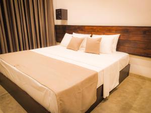 1 dormitorio con 1 cama grande con sábanas y almohadas blancas en Isi Arana Eco Villa, en Anuradhapura