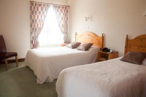 two beds in a hotel room with a window at Grovemount House in Ennistymon