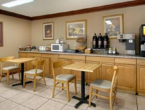 un restaurante con mesas y sillas de madera y una barra en Super 8 by Wyndham Breaux Bridge, en Breaux Bridge
