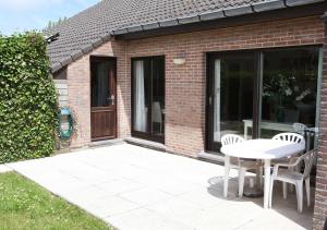 a patio with a table and chairs in front of a house at Westhinder in Wenduine