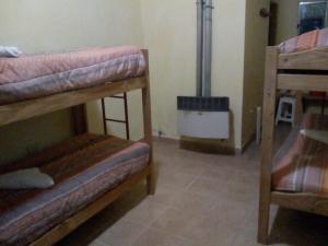 um quarto com 2 beliches e um aquecedor em Milenarios Hostel em El Chaltén