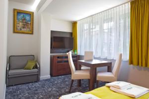 Pokój hotelowy ze stołem, krzesłami i telewizorem w obiekcie WISŁA Cechini w mieście Krynica Zdrój