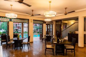 a dining room with tables and chairs and chandeliers at Lazy Lagoon, Baga A Lemon Tree Resort, Goa in Baga