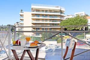 une table avec une assiette de nourriture sur un balcon dans l'établissement Colline Azur YourHostHelper, à Cannes