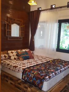 ein großes Bett in einem Schlafzimmer mit Fenster in der Unterkunft OMAH LUMUT Malang, Best Family Villa 3 Bedrooms Free Pool Kolam Renang in Malang