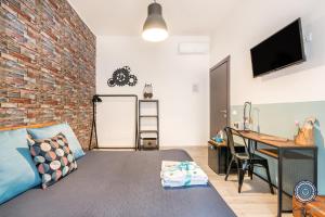 a room with a brick wall and a bed and a desk at La Casa dei Treni Affittacamere city rooms for travel lovers in La Spezia
