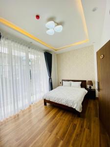 um quarto com uma cama com lençóis brancos e pisos em madeira em Mỹ Lan hotel em Da Lat