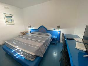 a bedroom with a blue bed and a desk at Hotel Guitgia Tommasino in Lampedusa