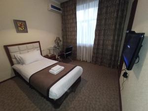 1 dormitorio con 1 cama, TV y ventana en Silk Way Boutique Hotel en Osh