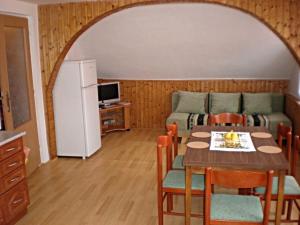a living room with a table and a couch and a refrigerator at Penzion "Apartmány U Semušky" in Pernink