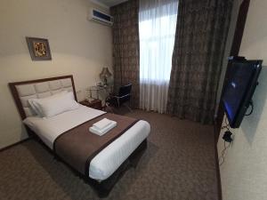 a hotel room with a bed and a television at Silk Way Boutique Hotel in Osh