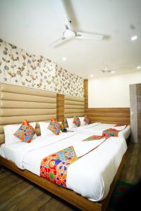 two beds in a room with white sheets and colorful pillows at Hotel Delhi Darshan Deluxe-By RSL Hospitality in New Delhi