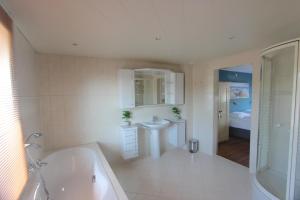 ein weißes Badezimmer mit Badewanne und Waschbecken in der Unterkunft Fijne vakantiehuizen 50 mtr van het strand in Egmond aan Zee + 68 Fotos