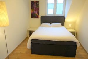 1 dormitorio con 1 cama con sábanas blancas y ventana en The Roof - Rooftop appt in historical center, en Amberes