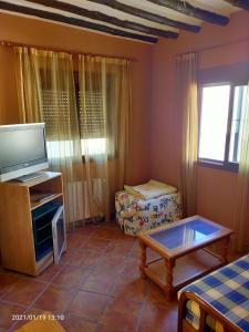 ein Wohnzimmer mit einem TV und einem Tisch in der Unterkunft Hotel Rural Real de Laroles Nevada bike and treeking in Laroles