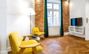 een woonkamer met 2 gele stoelen en een tv bij 2BCOMFY - Nad Niprem in Bielsko-Biala
