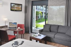 ein Wohnzimmer mit einem Sofa und einem Schreibtisch mit einem Laptop in der Unterkunft Hotel Eden Park Pau Est, avec Piscine in Pau