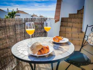 a table with two glasses of orange wine and croissants at Cabanas Terraces - Pool and seaview in Tavira