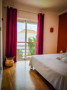 a bedroom with a bed and a window with red curtains at Cabanas Terraces - Pool and seaview in Tavira