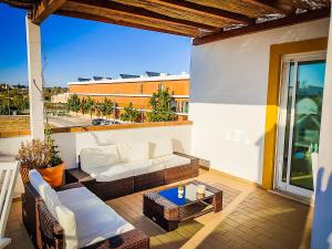 a patio with a couch and a table on a balcony at Cabanas Terraces - Pool and seaview in Tavira