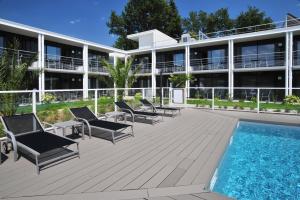 un complexe avec une piscine, des chaises et un bâtiment dans l'établissement Hotel Eden Park Pau Est, avec Piscine, à Pau