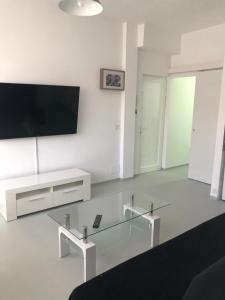 a white living room with a tv and a glass table at APARTAMENTO CENTRAL 1 in Corralejo
