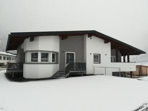 a small white house with a porch in the snow at Das Stuiben in Umhausen