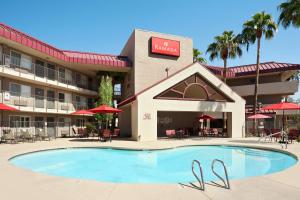 a hotel with a swimming pool in front of a hotel at Ramada by Wyndham Tempe/At Arizona Mills Mall in Tempe