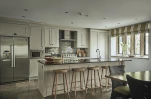 a kitchen with white cabinets and a island with bar stools at Oughtershaw Hall in Beckermonds