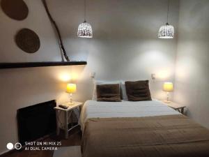 a bedroom with a bed and two lamps and a tv at Casa do Castelo - Zona Histórica in Mértola